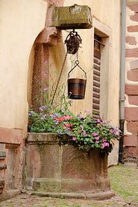 Fountain with bucket and flowers in France