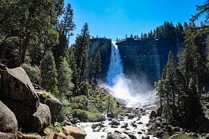A powerful waterfall cascading down a cliff surrounded by evergreens, capturing the spirit of epic outdoor adventures in Yosemite.