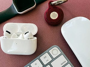 Apple AirPods, keyboard and mouse on a desk for traveling to Europe with electronics and to pass the time during an airport layover.