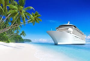 A large white cruise ship anchored near a tropical beach with palm trees and bright blue water, highlighting cruise tips and tricks.