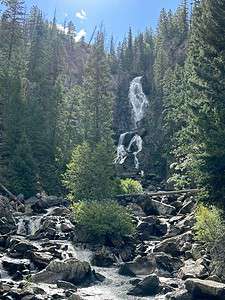 Fish Creek Falls cascading over rocky cliffs surrounded by pine trees in Steamboat Springs Colorado a summer vacation in Colorado highlight.