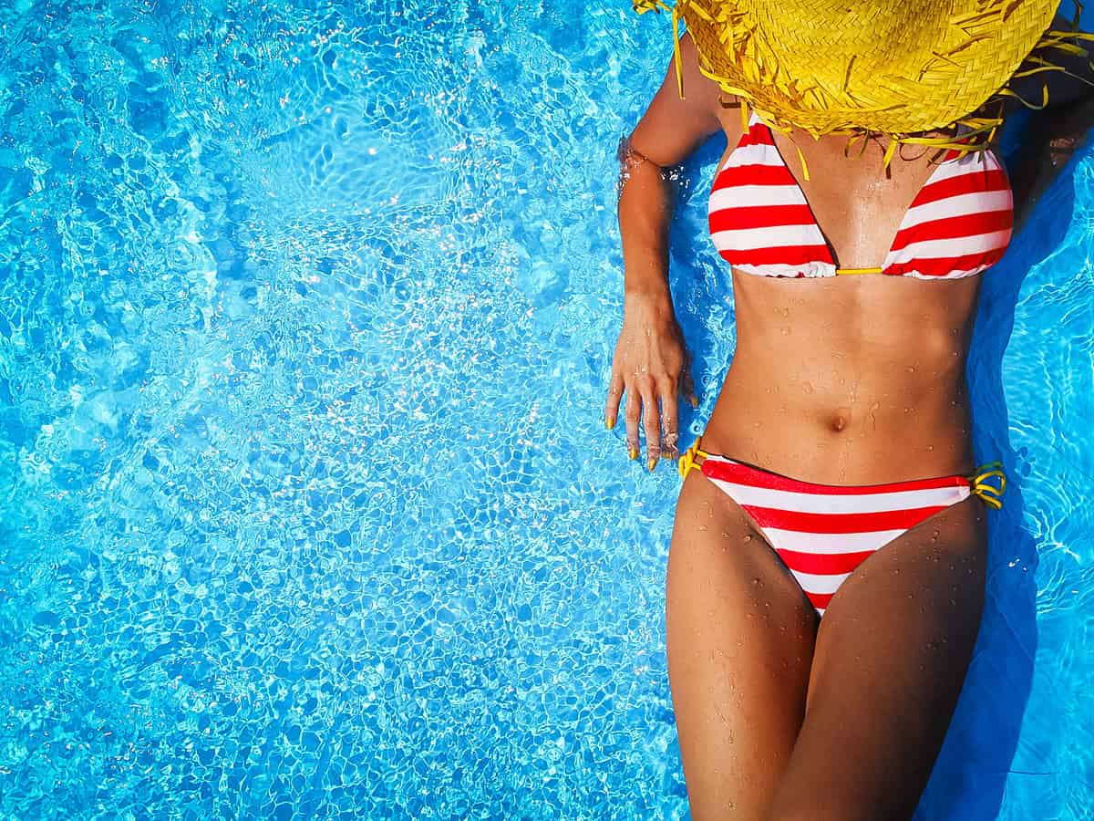 woman in red and white striped bikini relaxing in a hot springs pool on a Colorado road trip stop and representing hot springs etiquette