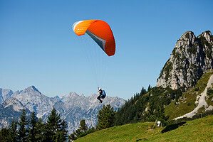 Paragliding Mt Pilatus with an orange paraglider soaring above the Swiss Alps.