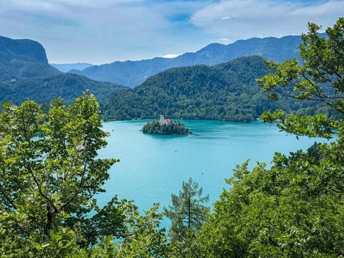 A serene lake with an island church surrounded by mountains and trees, perfect for a guide to ljubljana to lake bled.