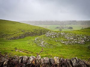 Green hillside along Winnats Pass on a cloudy day.