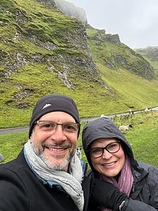 Couple hiking in Winnats Pass in the Peak District, UK with sheep in the background.