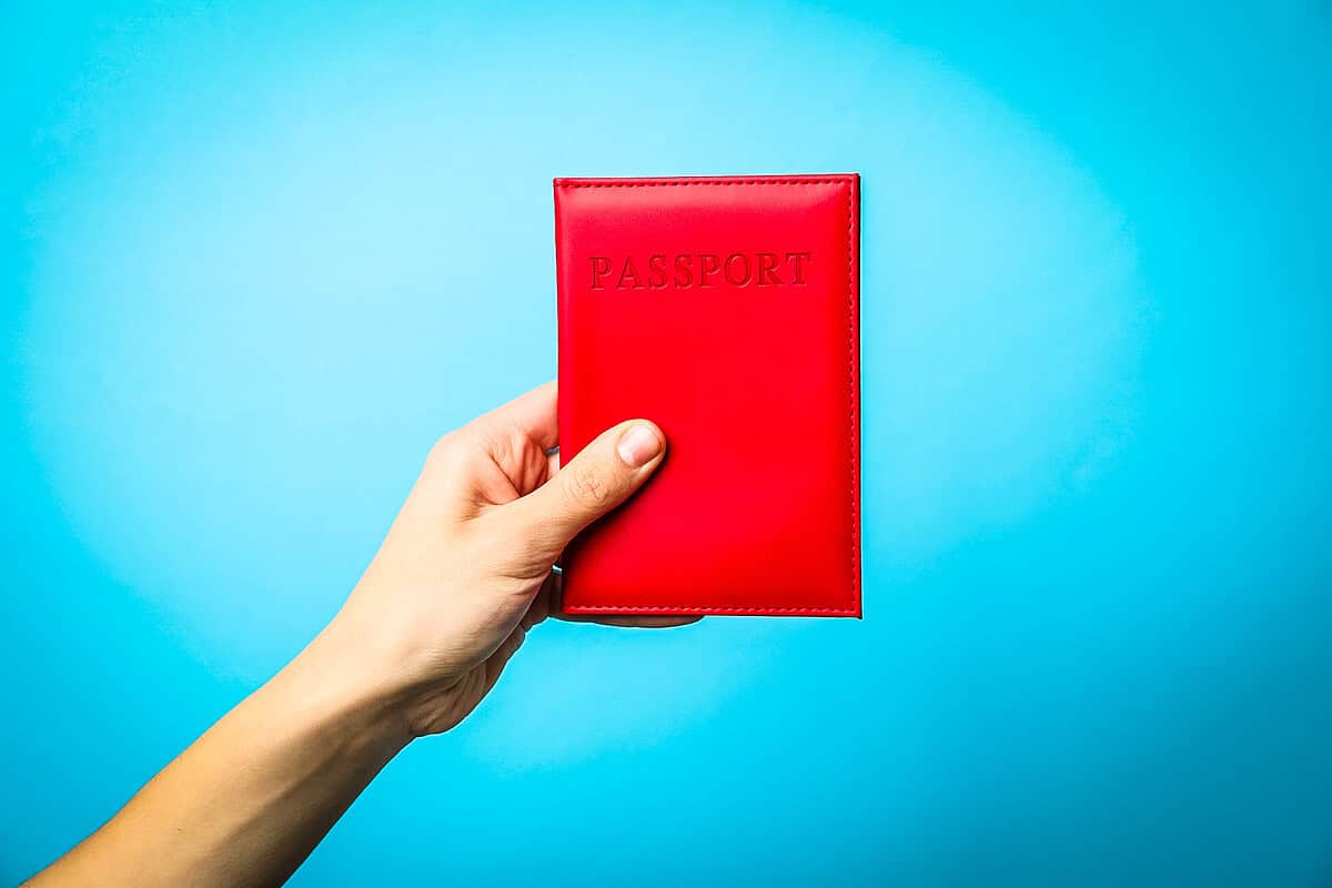 Hand holding a passport cover, symbolizing travel preparation and document safety.