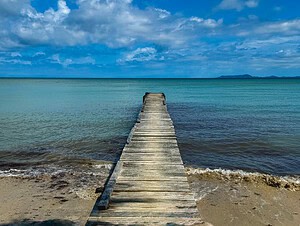Weathered wooden dock stretching into calm turquoise waters under a dramatic blue sky in Panama—perfect for a Panama vs Costa Rica comparison post.