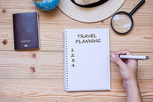 How to plan an international trip checklist with notebook, passport, and magnifying glass on a wooden table