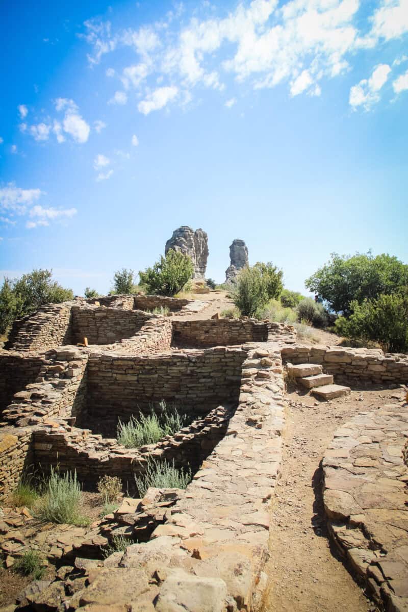 The Great House Pueblo ruins at Chimney Rock National Monument, with Chimney Rock and Companion Rock rising in the background.