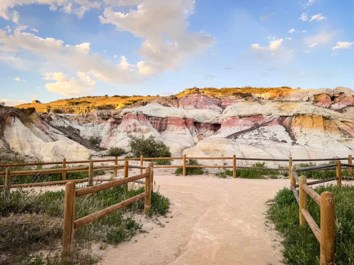 Wooden fence along the trail leading toward colorful sandstone formations at Paint Mines Colorado.