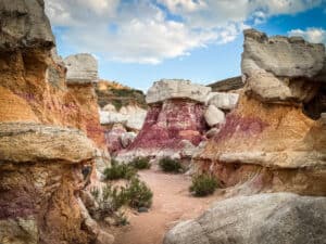 Looking through towering sandstone rock walls at a colorful hoodoo formation at Paint Mines Colorado.