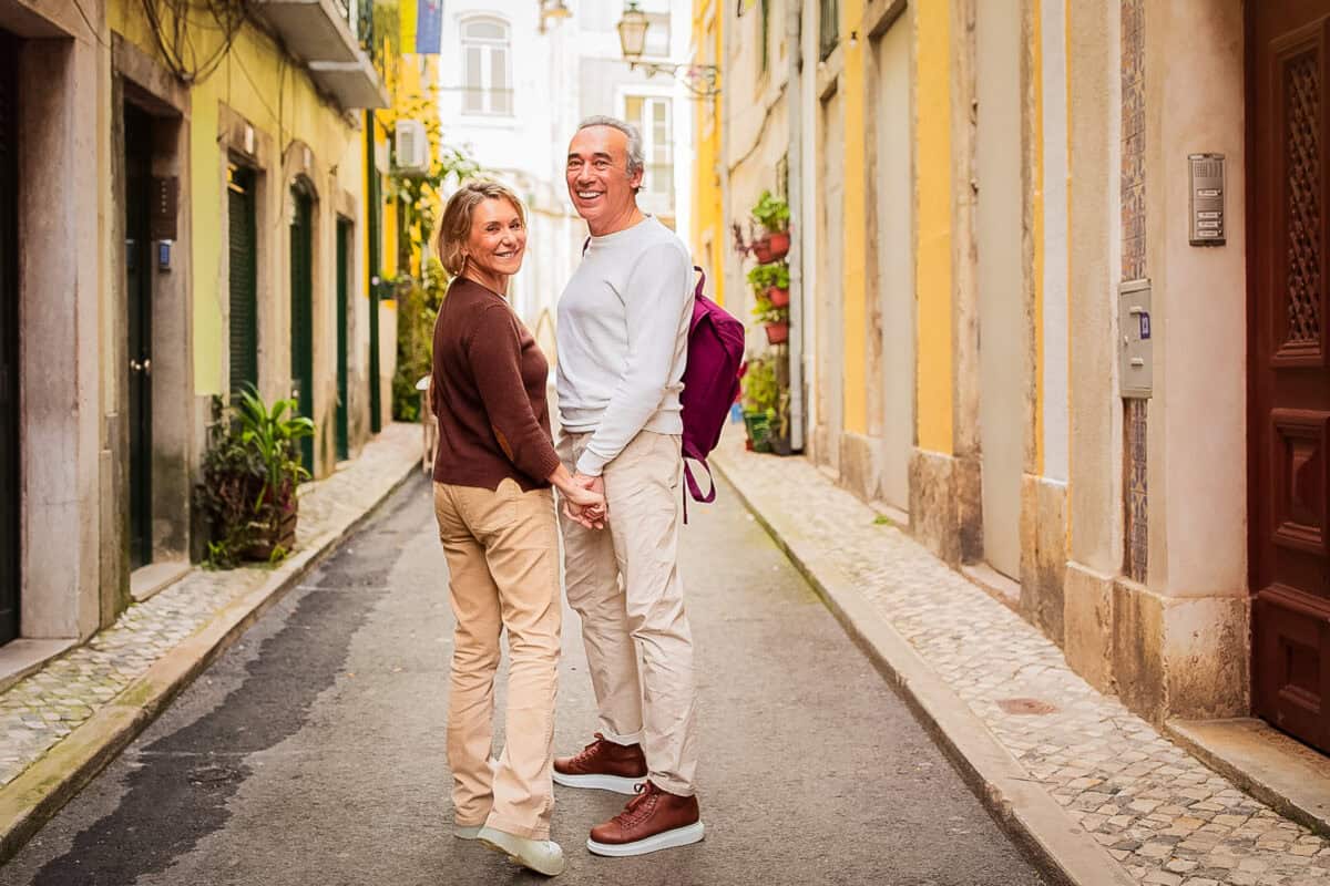 20260705 funquestionstoaskyourpartner 5000 Mature couple holding hands in a colorful European alley, an example of the travel moments perfect for fun questions to ask your partner.