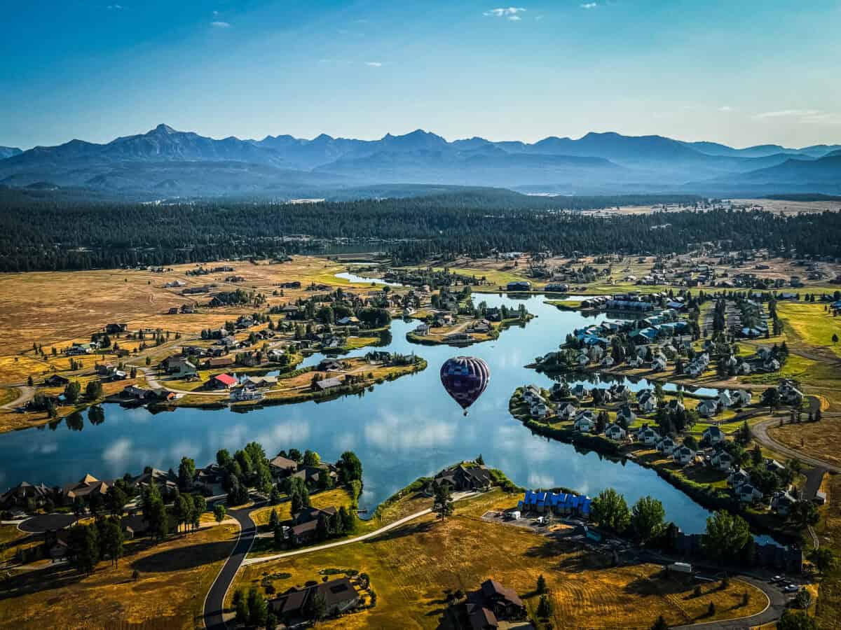 Aerial view of the Pagosa Springs valley and river from a hot air balloon, with mountains in the background.