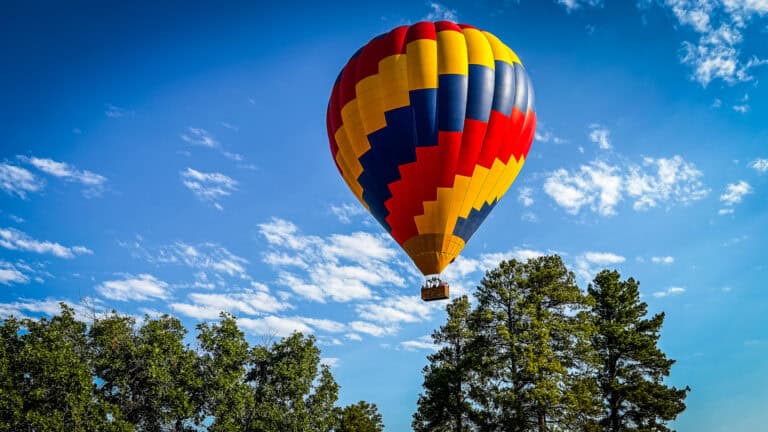 20260711 pagosaspringshotairballoons1 1343 Pagosa Springs hot air balloons rising over the pines with the San Juan Mountains in the background.