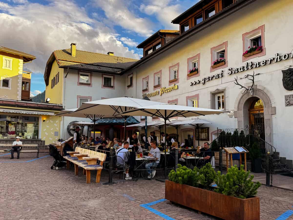 20260822 wheretostayinthedolomites 2217 Hotel Garni Snaltnerhof, a bed-and-breakfast in Ortisei, Val Gardena, Italy, with flower-lined windows and outdoor dining below.