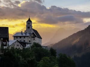Where to stay in the Dolomites Italy: sunrise view of the chapel and village of Colle Santa Lucia from my vacation rental window.