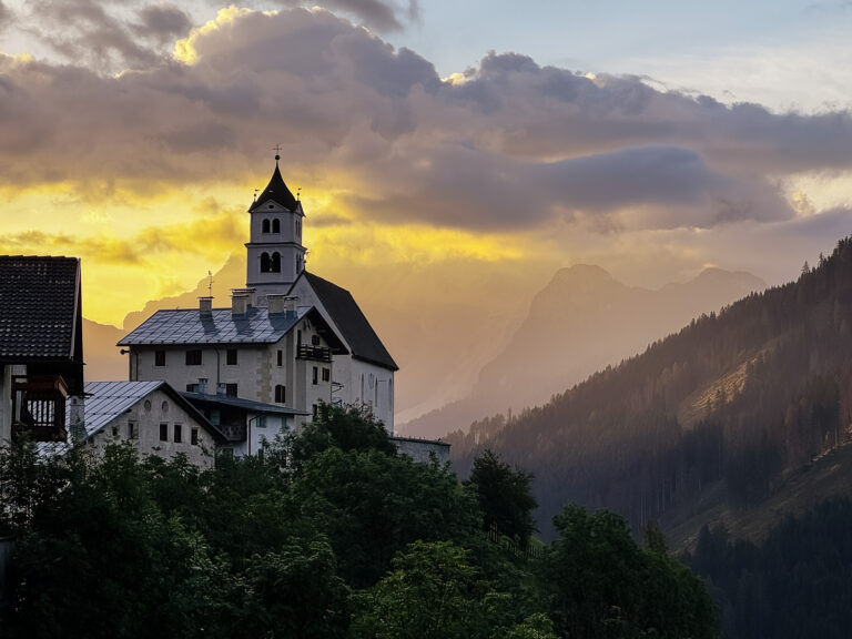 Where to stay in the Dolomites Italy: sunrise view of the chapel and village of Colle Santa Lucia from my vacation rental window.