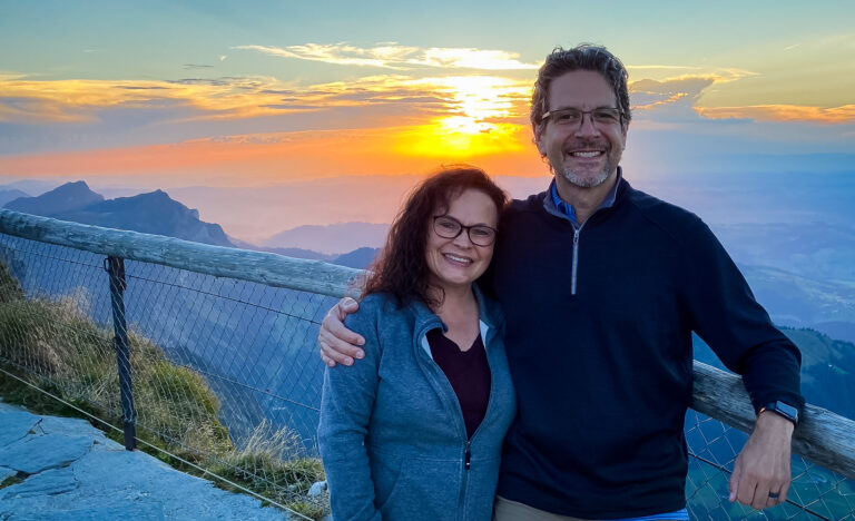 Couple smiling together at sunset on Mt. Pilatus in Switzerland, an example of how to take better travel photos and look good in them.