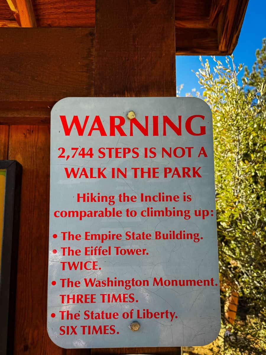A warning sign at the Manitou Incline trailhead stating that 2,744 steps is not a walk in the park and comparing the climb to the Empire State Building and Eiffel Tower.